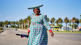 Eine einheimische Frau in traditioneller Kleidung überquert eine Strasse.
