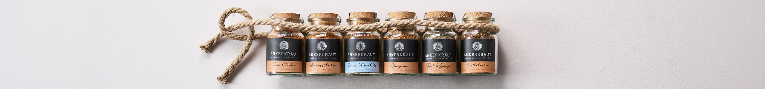 Vier Korkengläser von Ankerkraut unter einer Banderole mit maritimem Print.