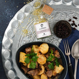 Lammragout, Kartoffeln und Rosinen in Schale, daneben Vadouvan-Gewürz auf dekorativem Tablett.